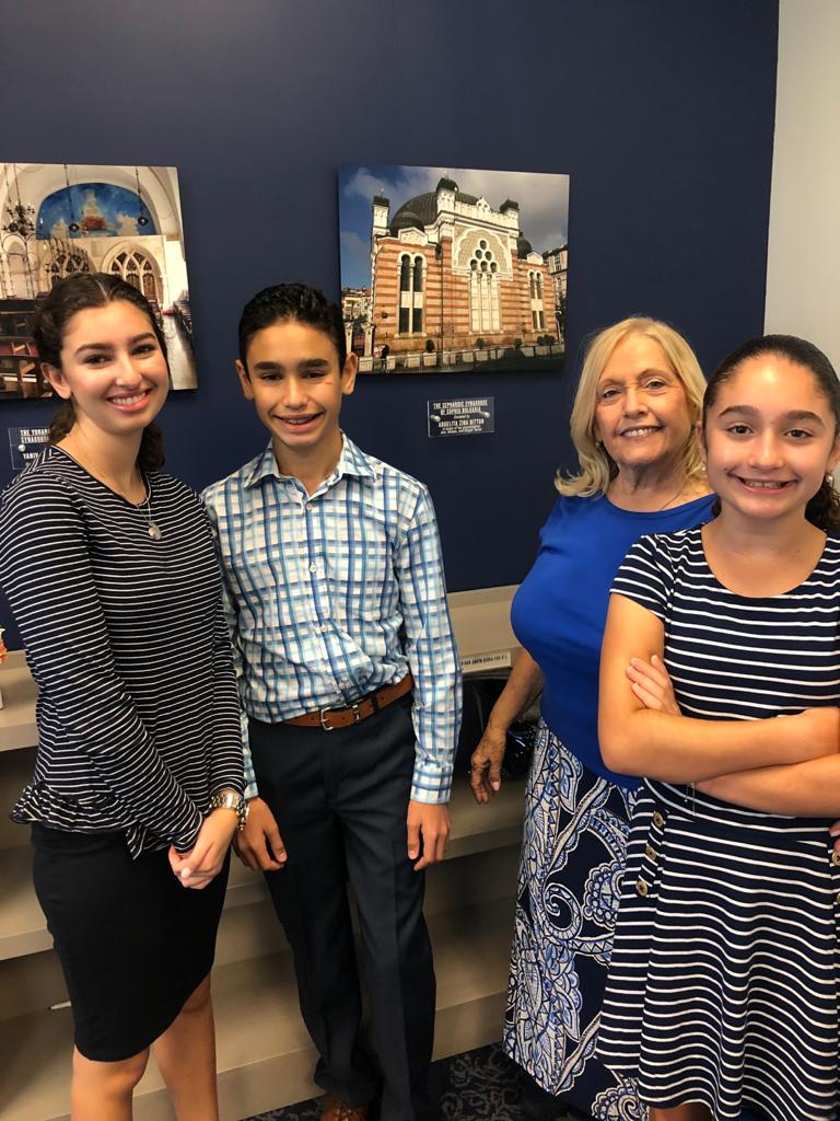 Students smiling beside a teacher at the chapter's exhibit of historic Sephardic synagogues.